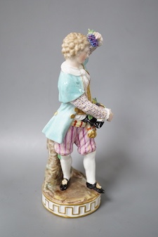 A 19th century Meissen figure of a boy holding grapes to his head, his hat full of grapes, wearing a crinoline scarf and shirt cuffs, crossed swords in blue, incise letters and numbers 17cm